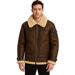 A man wearing a brown leather aviator-style jacket with a thick beige shearling collar, cuffs, and hem, paired with black pants, against a plain white background.